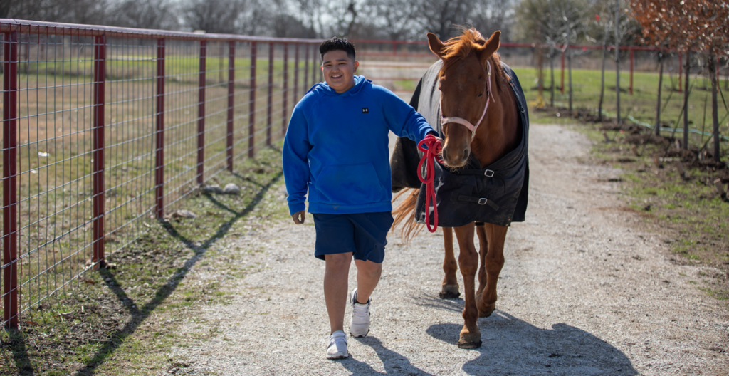 Person guiding horse along dirt path.