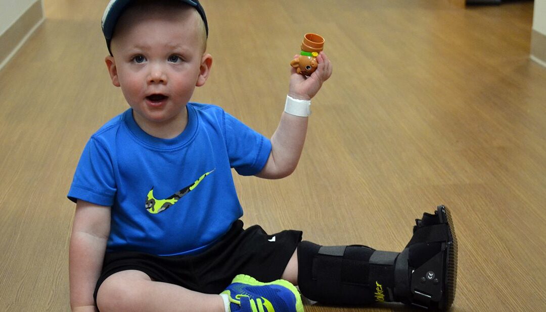 Toddler with a broken foot plays with toys