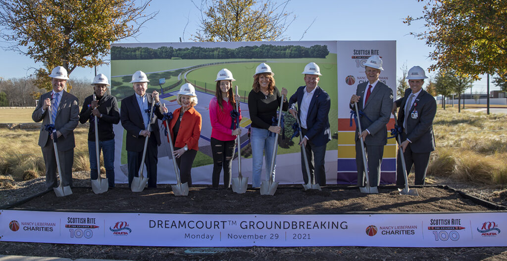 A group of people holding shovels in front of a sign that says dreamcourt groundbreaking | NANCY LIEBERMAN CHARITIES SCOTTISH RITE FOR COFLOP 100 10% ADLETA Cahashi SCOTTISH RITE 10 NANC CH MAN S DREAMCOURTTM GROUNDBREAKING Monday November 29 NANCY LIEBERMAN CHARITIES 2021 SCOTTISH RITE FOR CHILORE 100 10 ADLETA