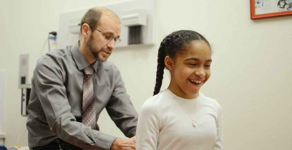 A young girl is smiling while being examined by a doctor