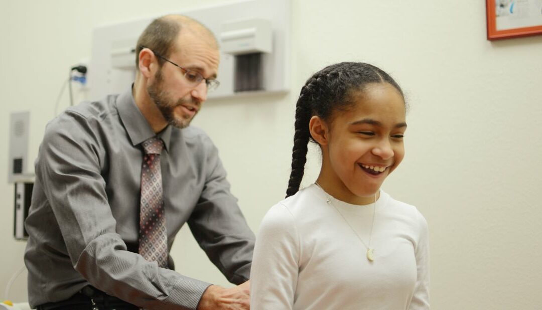 A young girl is smiling while being examined by a doctor