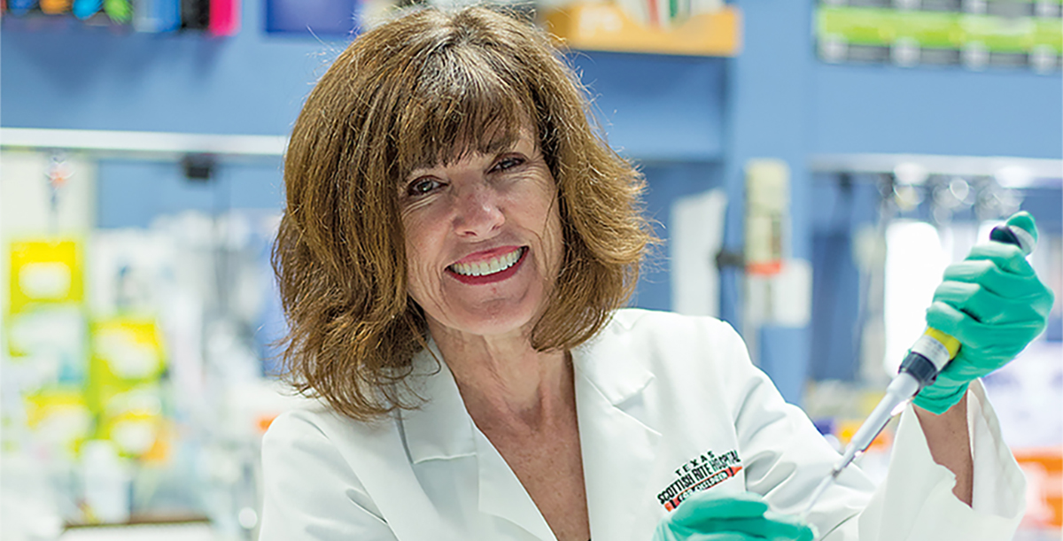 dark headed woman wearing gloves holds a DNA sample