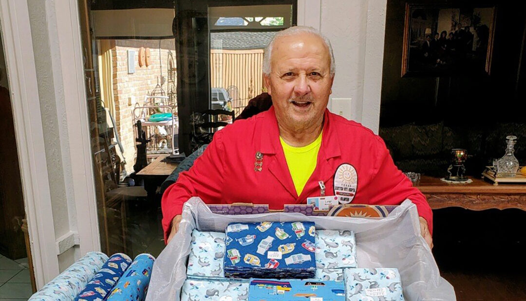 A man in a red jacket holds a box of wrapping paper