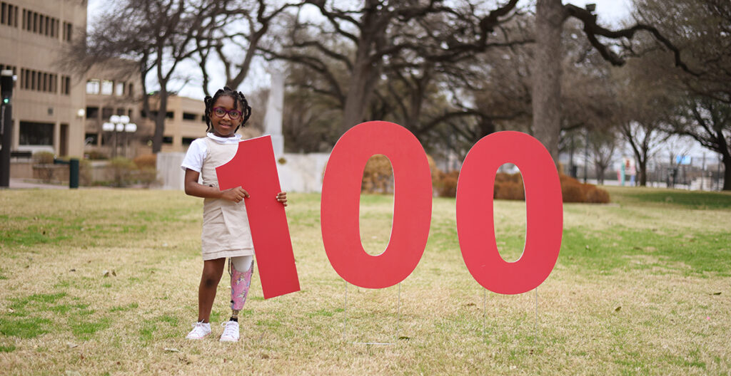 Girl in field with 100 sign